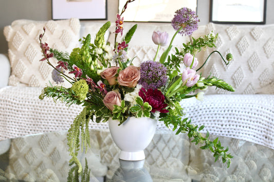 Soft blush floral arrangement with mauve, blush, and lavender blooms in a ceramic vase.