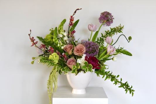 Soft blush floral arrangement with mauve, blush, and lavender blooms in a ceramic vase.